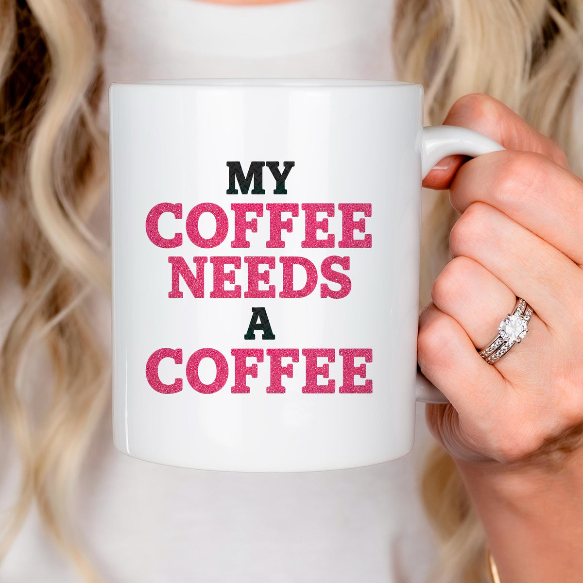 White ceramic mug held by hand, printed "MY COFFEE NEEDS A COFFEE" text