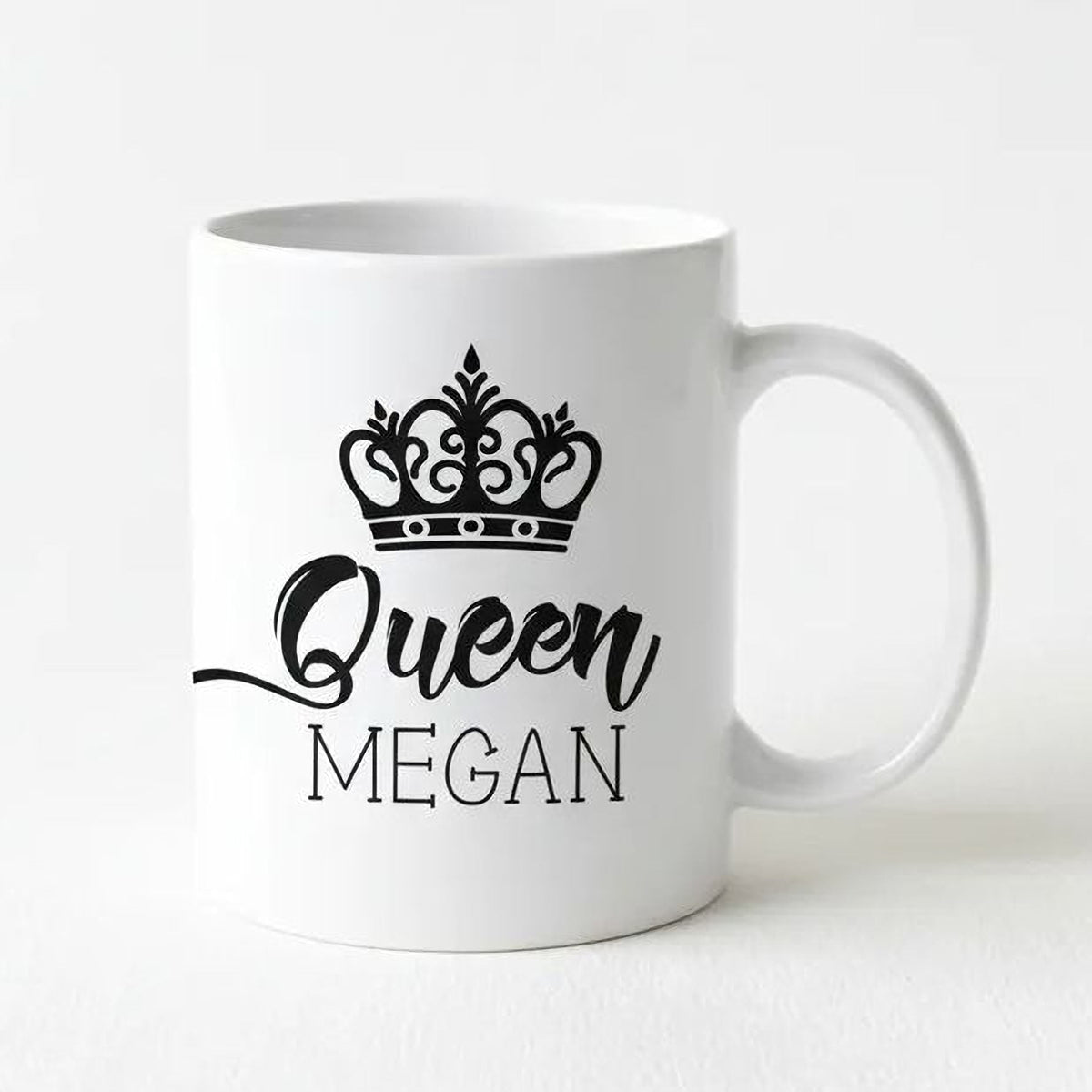 White ceramic coffee mug with black crown icon and “Queen” name print, right-side handle.