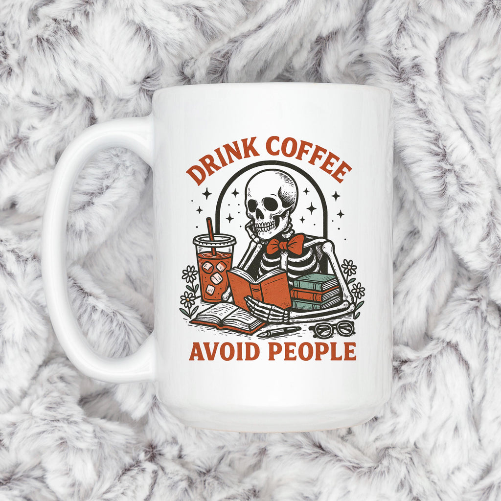 White coffee mug with skeleton illustration and red 'Drink coffee' and 'Avoid people' lettering