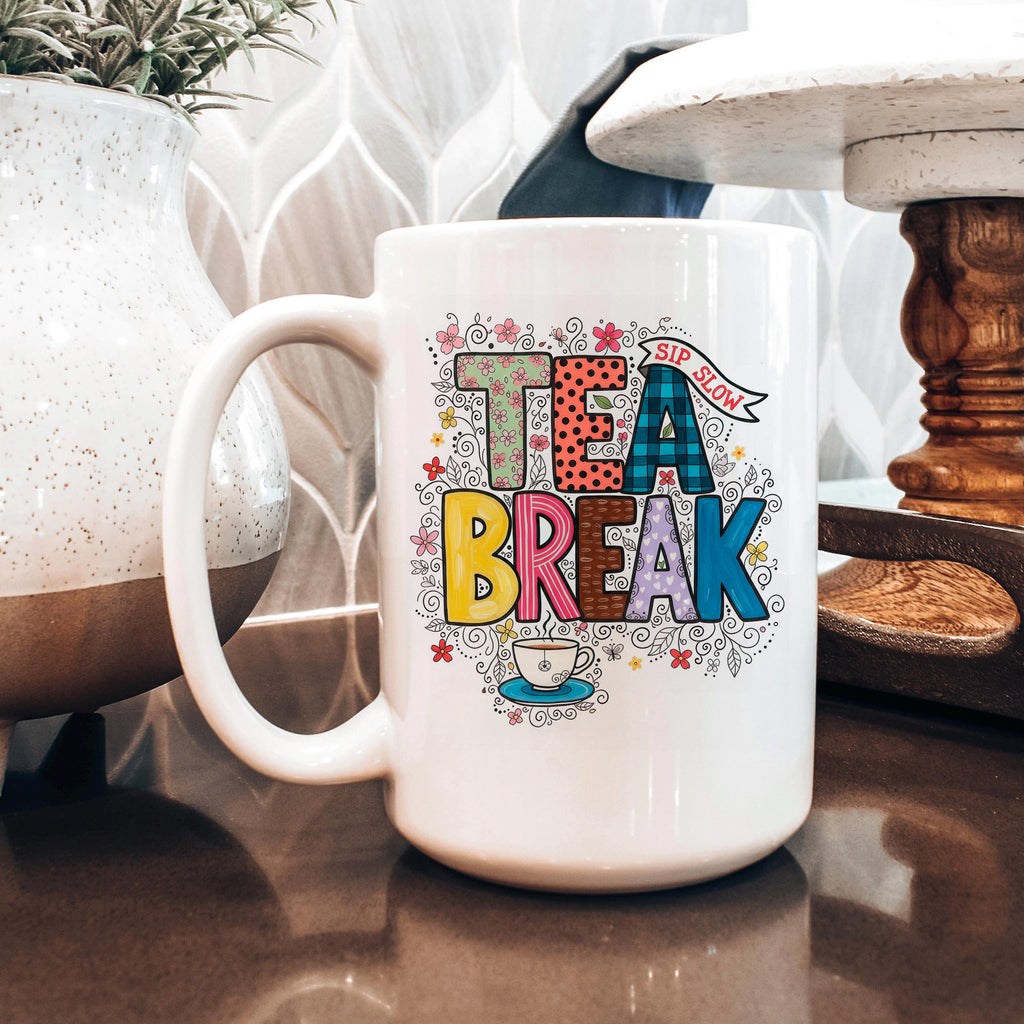 White ceramic tea mug with 'TEA BREAK' colorful floral graphic and side handle