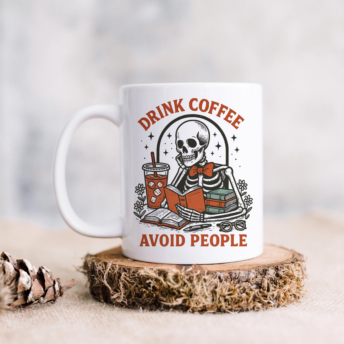 White coffee mug with skeleton artwork and bold red 'Avoid people' text on front
