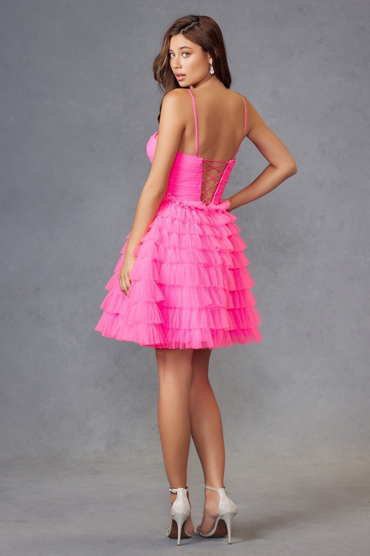 Neon pink tulle ruffle cocktail dress from back view with thin straps and tiered skirt
