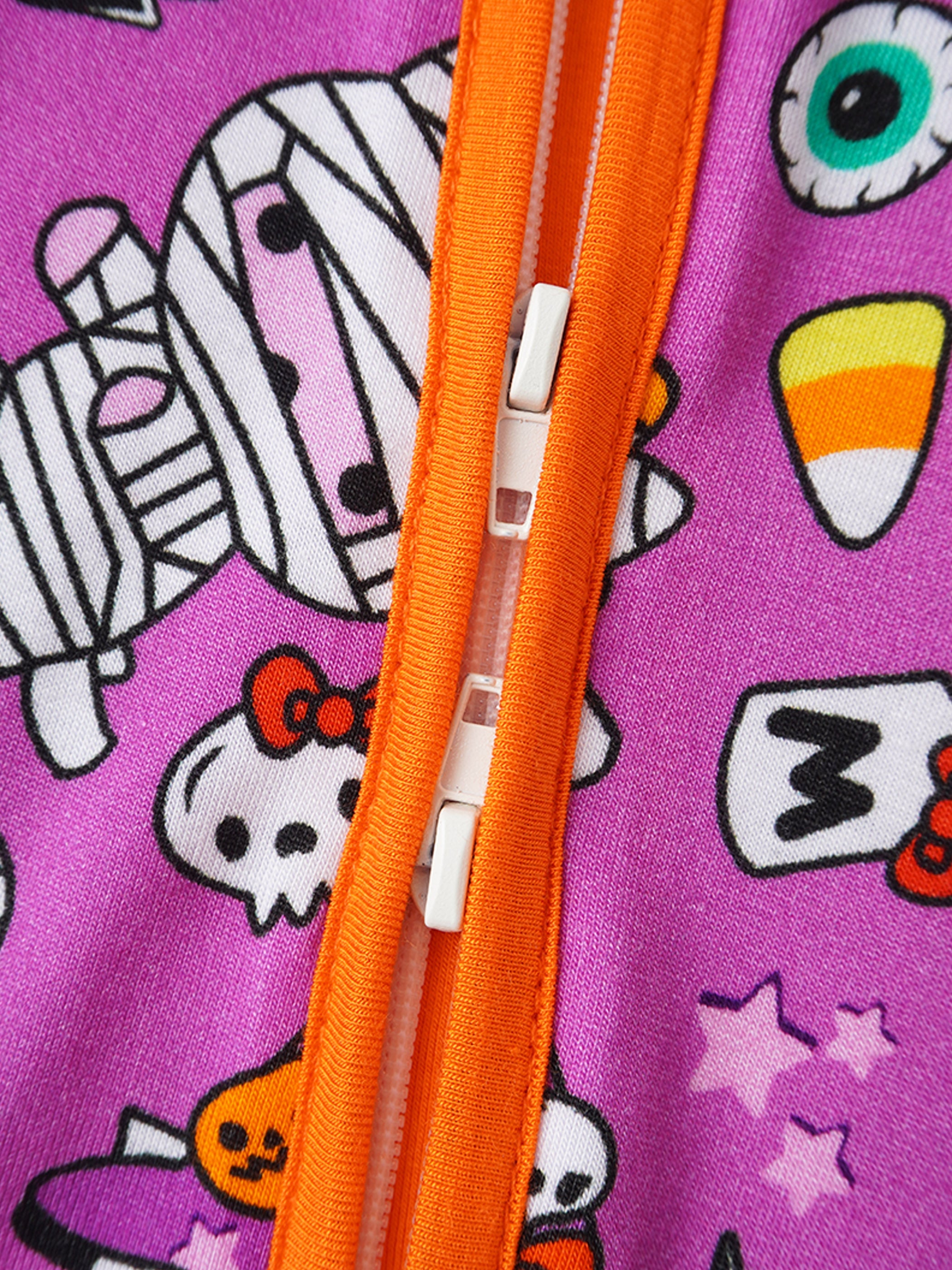 Baby romper close-up of orange zipper with white pull tab and purple cartoon print