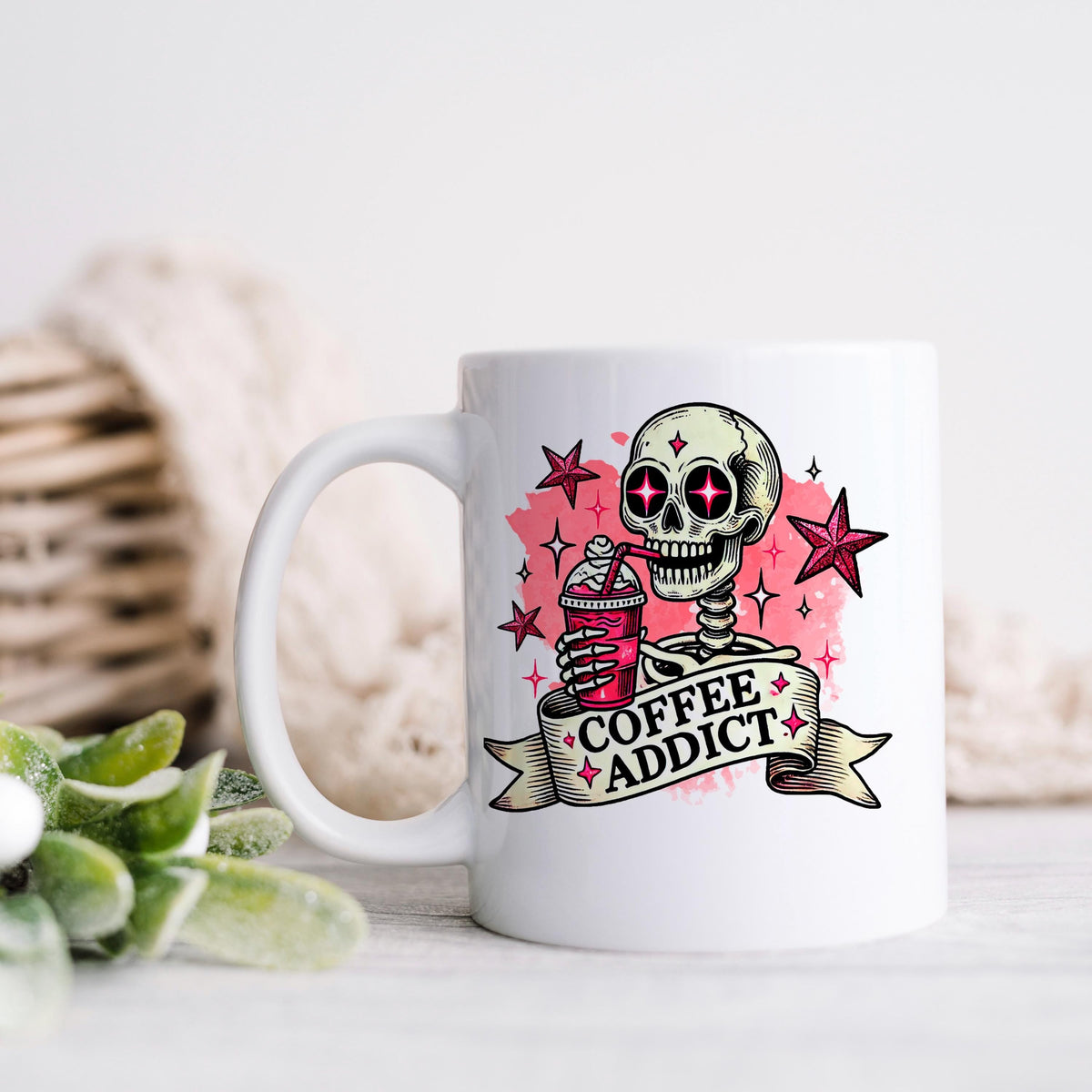 White ceramic coffee mug with pink skull 'Coffee Addict' design, handle on left side