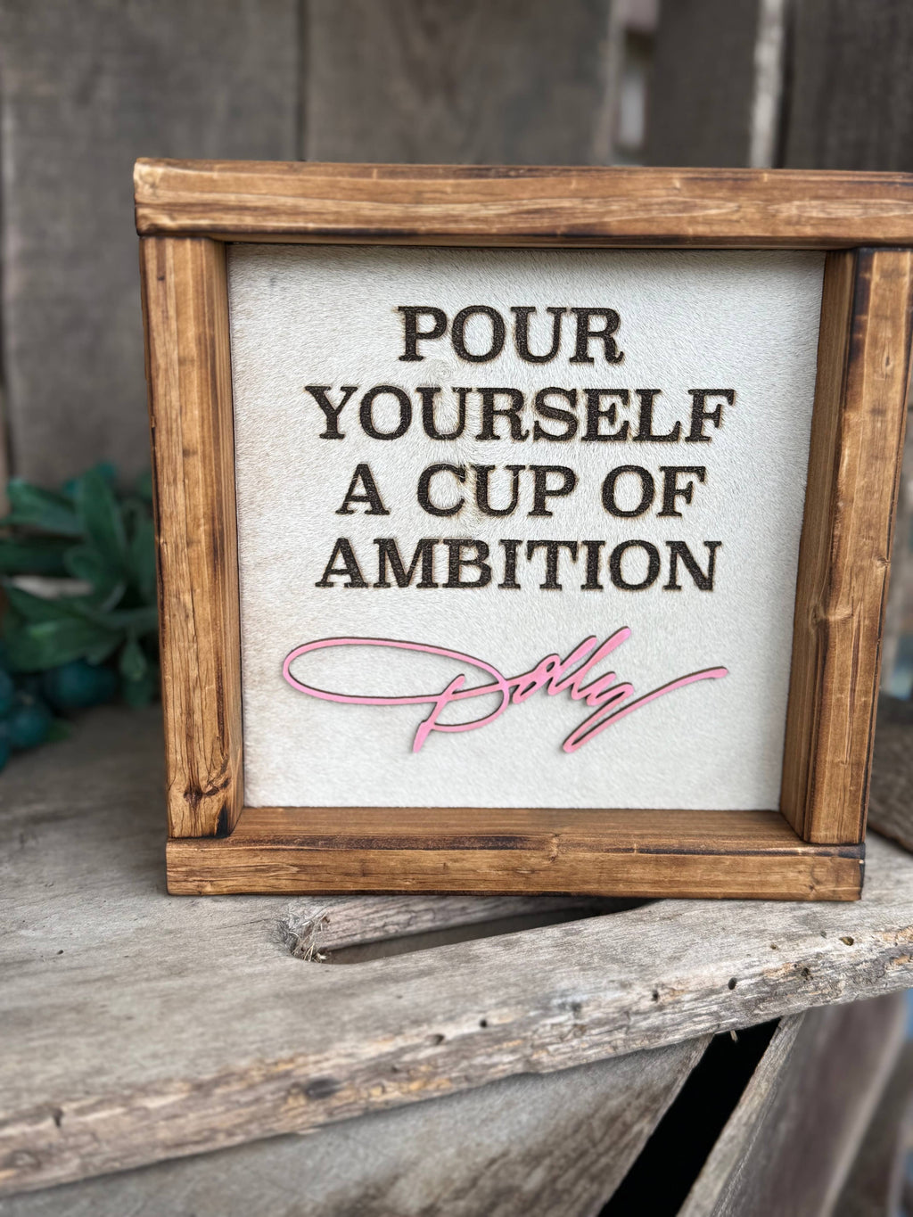 Framed cowhide wall sign, 'POUR YOURSELF A CUP OF AMBITION' with script signature