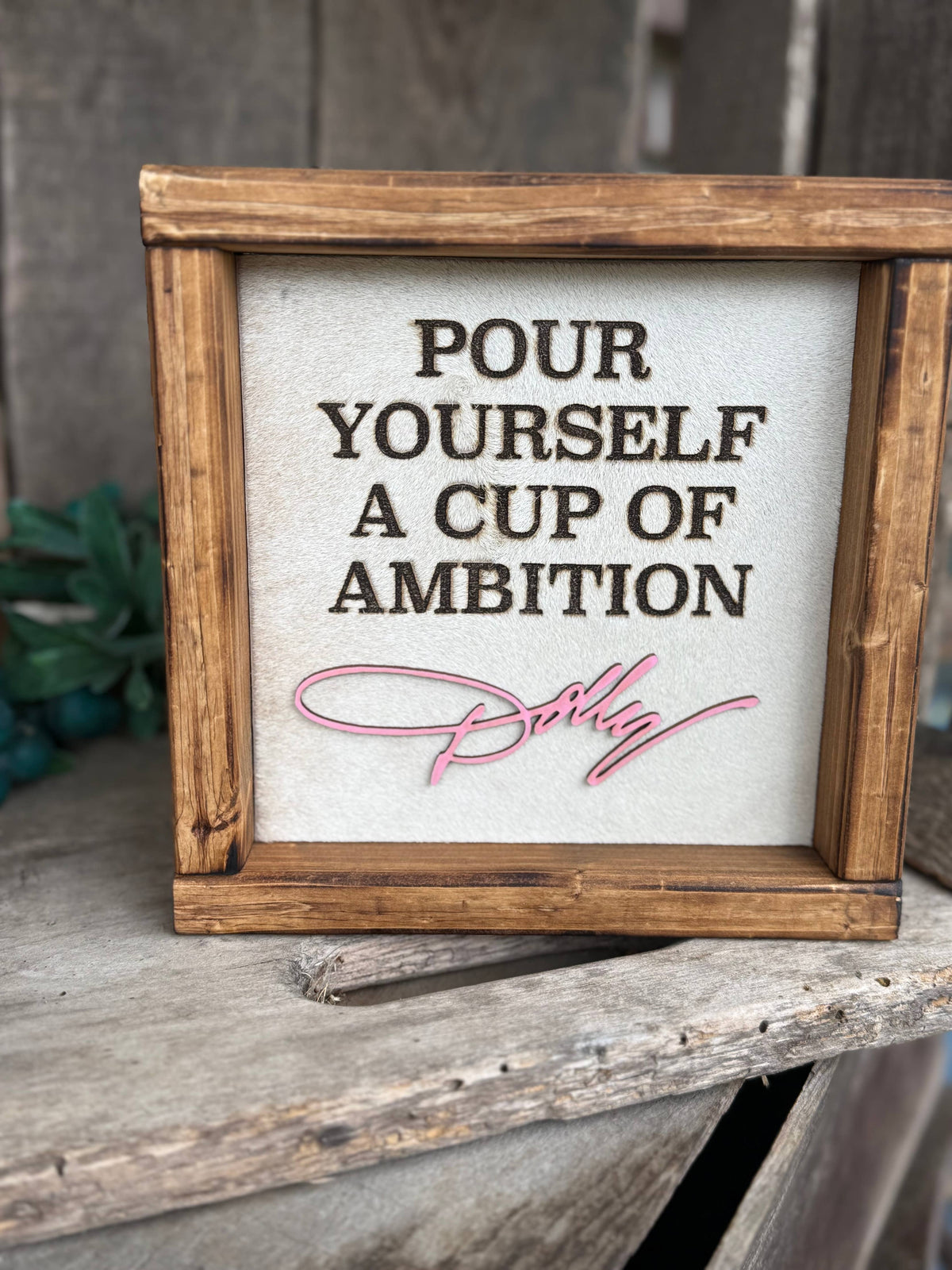 Framed cowhide wall sign, 'POUR YOURSELF A CUP OF AMBITION' with script signature