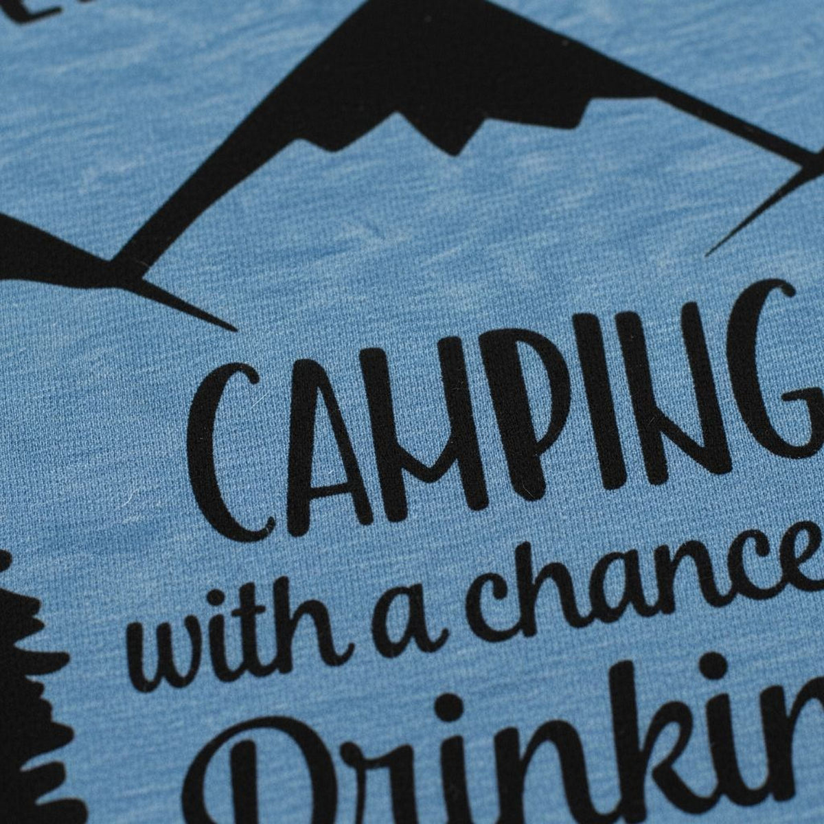 Close-up of “CAMPING” and “chance of Drinking” print on a blue t-shirt