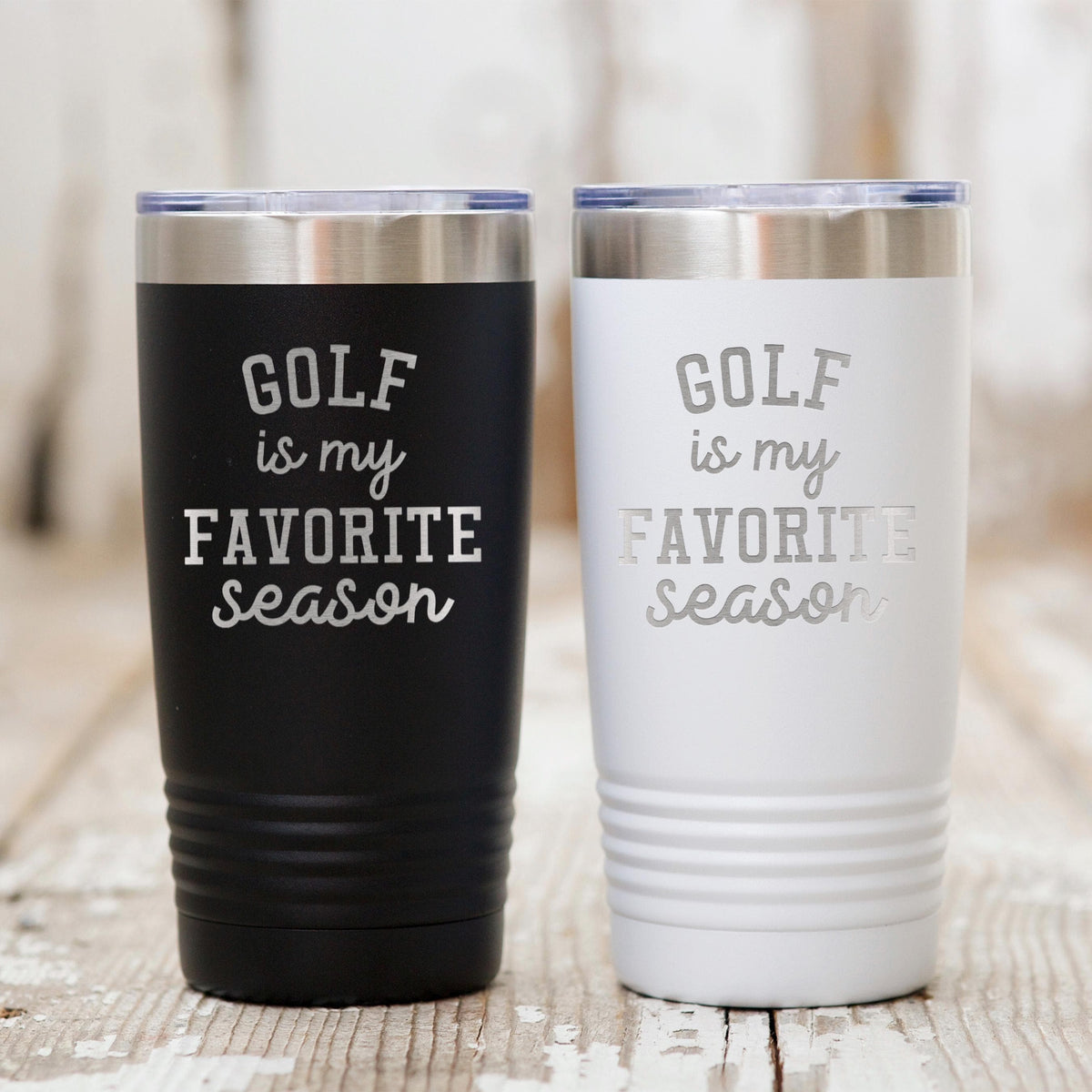 Insulated travel tumblers in black and white stainless steel with 'GOLF is my favorite season'