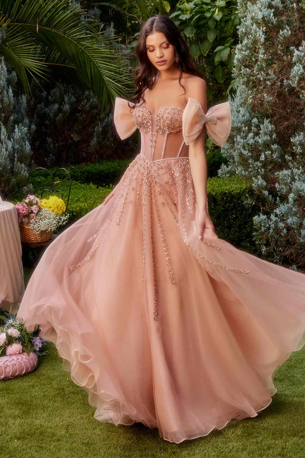 Rose gold strapless beaded gown with ornate bodice, bow arm bands, and voluminous tulle skirt.