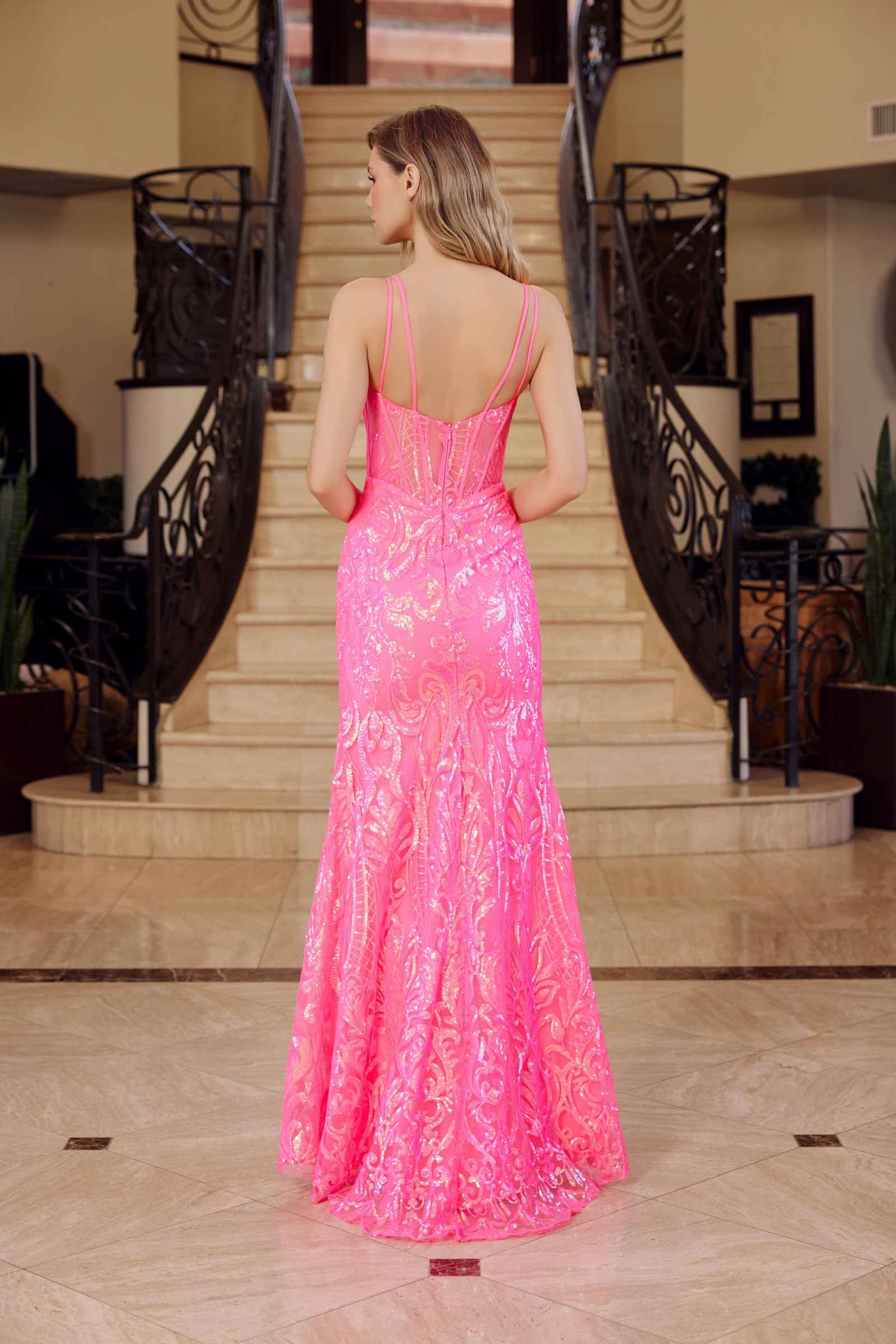 Hot pink sequined sleeveless gown from the back with long fitted silhouette.