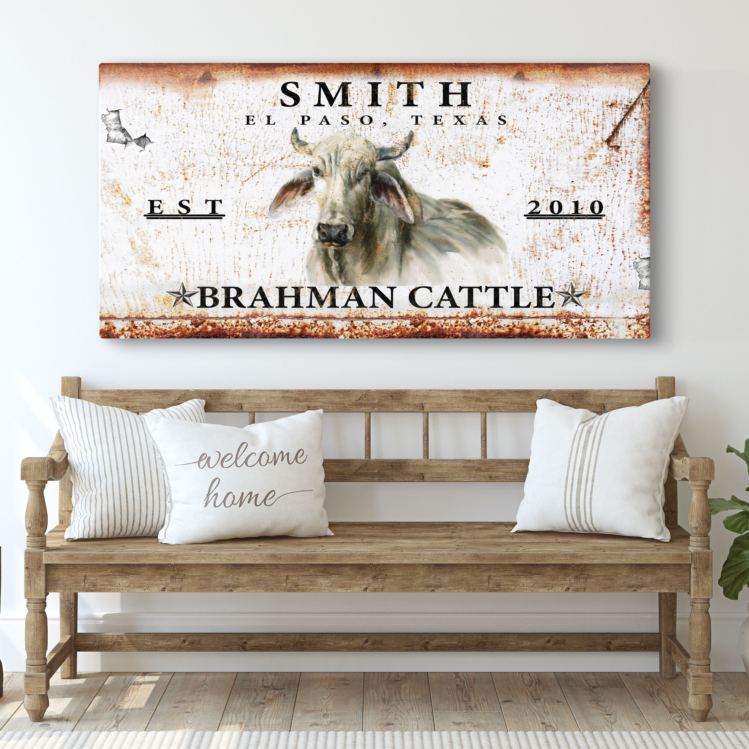 Rustic landscape canvas wall sign with bull and calf illustration above couch pillows