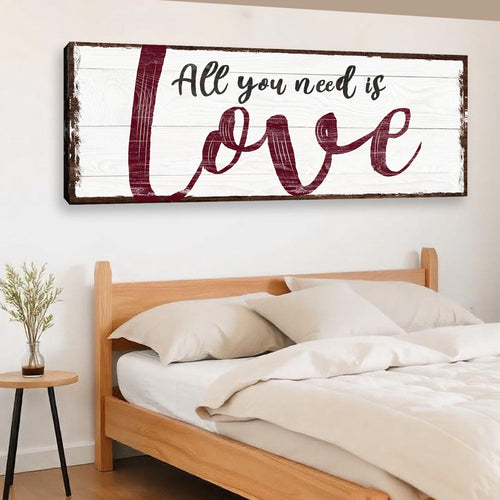 Framed wall canvas sign with burgundy “All you need is love” script on white wood texture