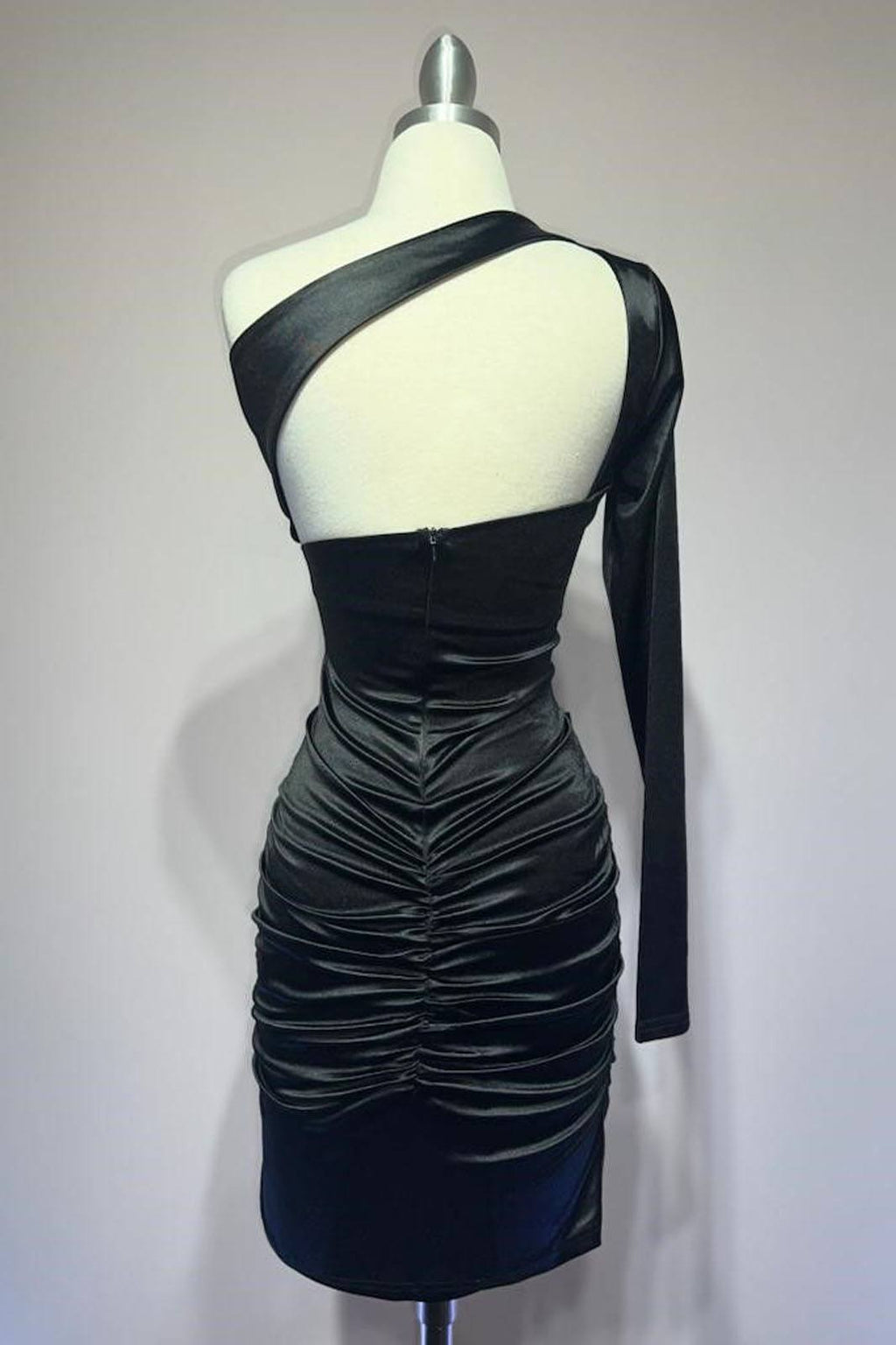 Black one-shoulder long-sleeve ruched cocktail dress on mannequin, open back