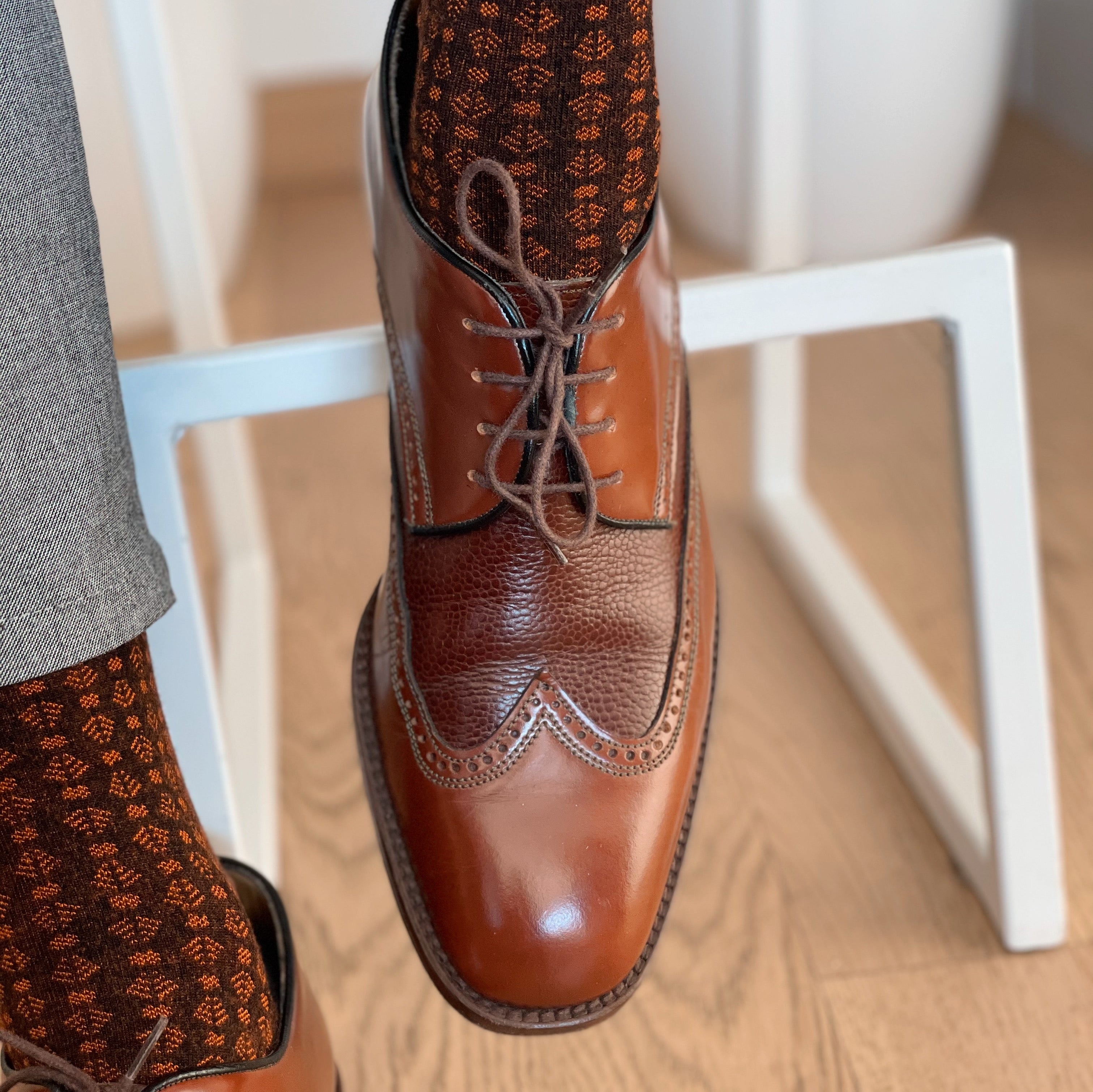Men's bamboo dress and trouser socks on foot, brown patterned sock with black toe/heel