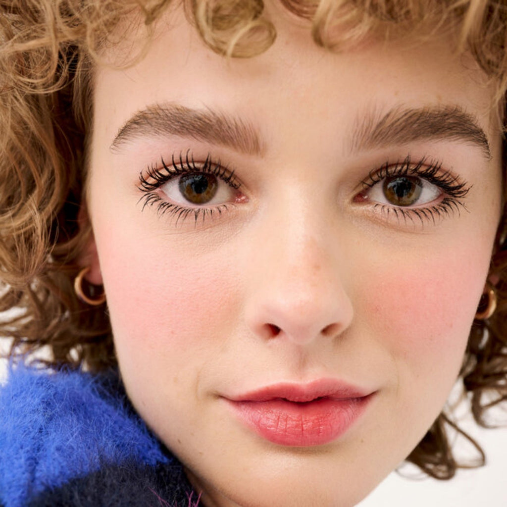 Applied mascara on lashes, enhancing volume and curl on green eyes