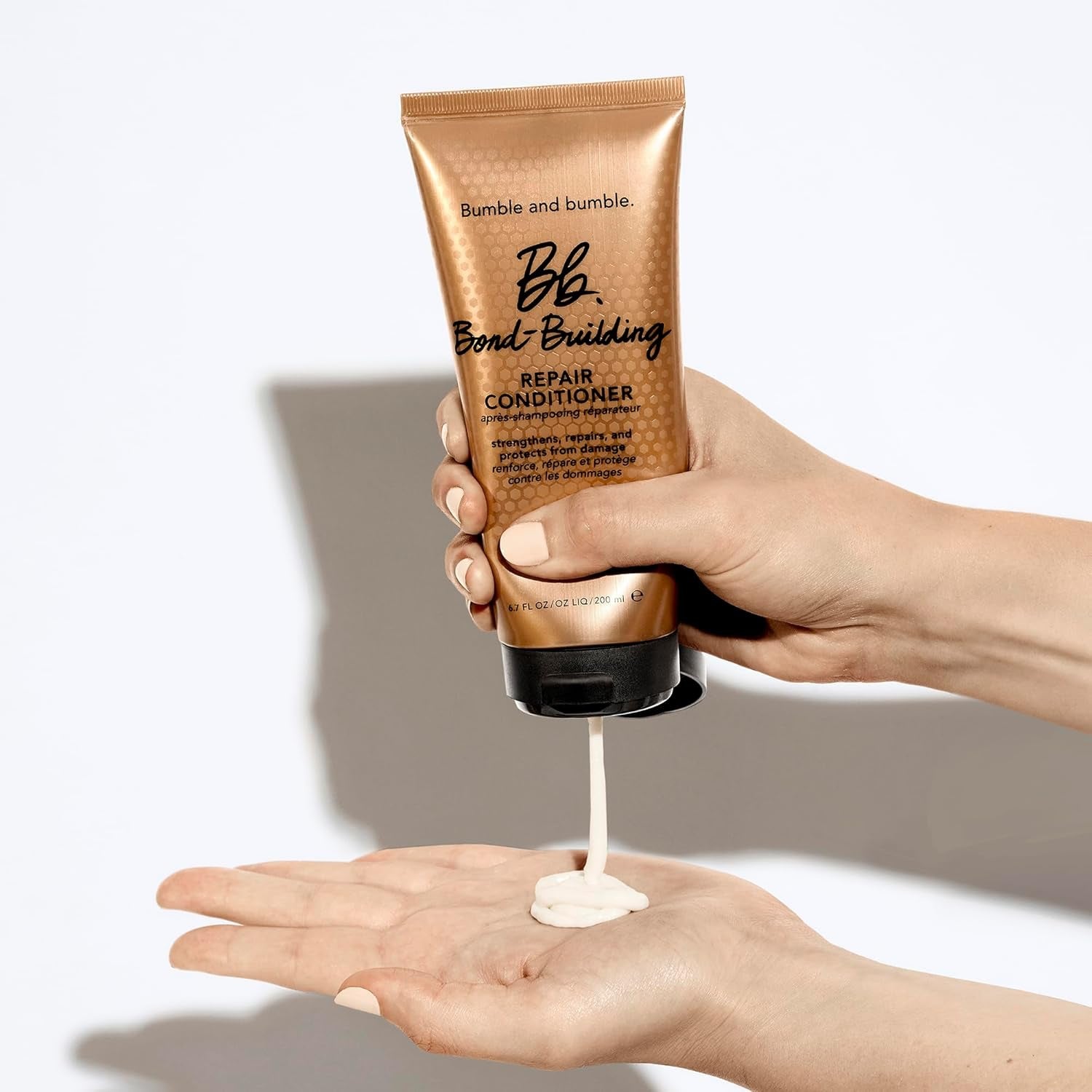 Bond-building repair conditioner dispensed from tube onto hands