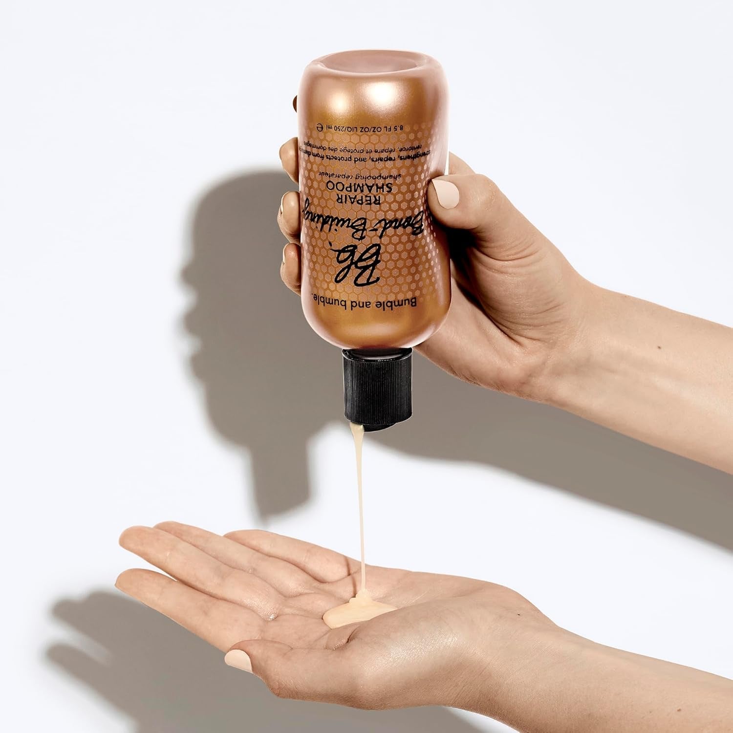 Bond-Building Repair Shampoo bottle held above palm as clear liquid pours