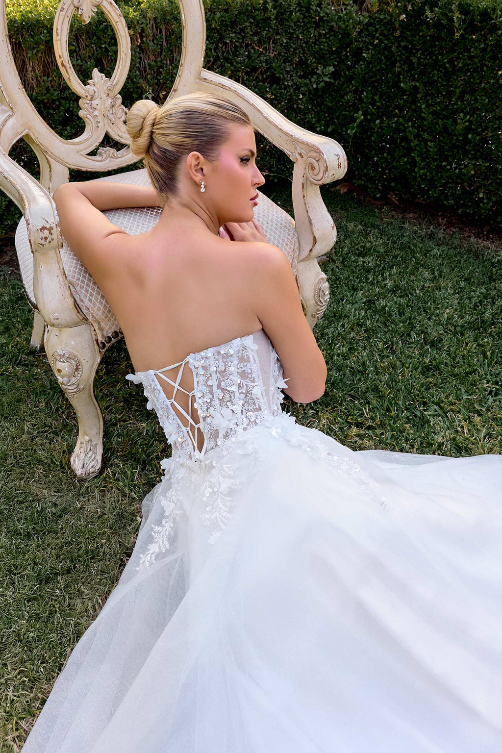 Off-white A-line gown with open back, lace straps, and 3D floral applique detailing
