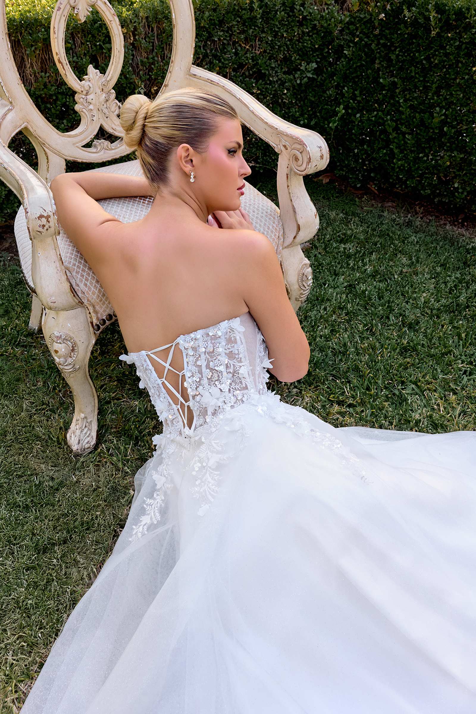 Off-white A-line gown with open back, lace straps, and 3D floral applique detailing