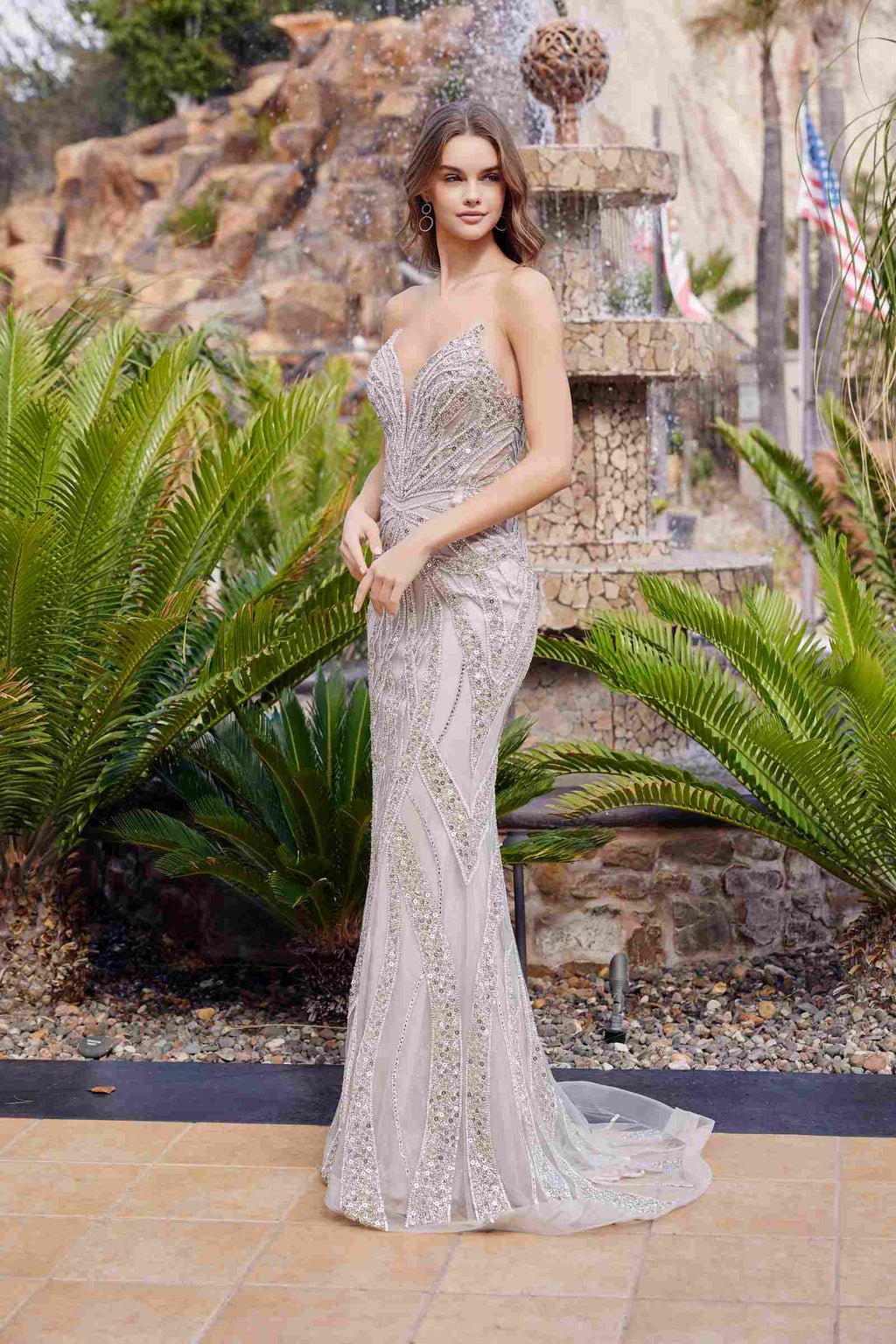 Silver strapless beaded prom gown with peaked neckline and long flowing skirt, fitted silhouette