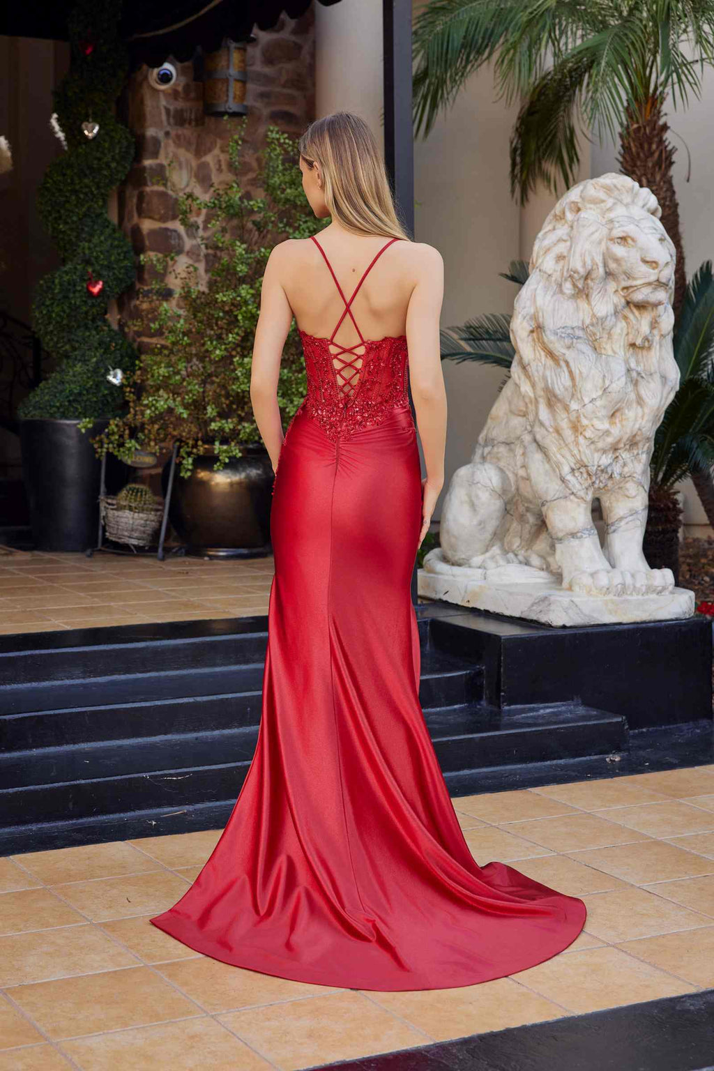 Red satin prom gown back view, crisscross strap detail, long skirt with flowing train