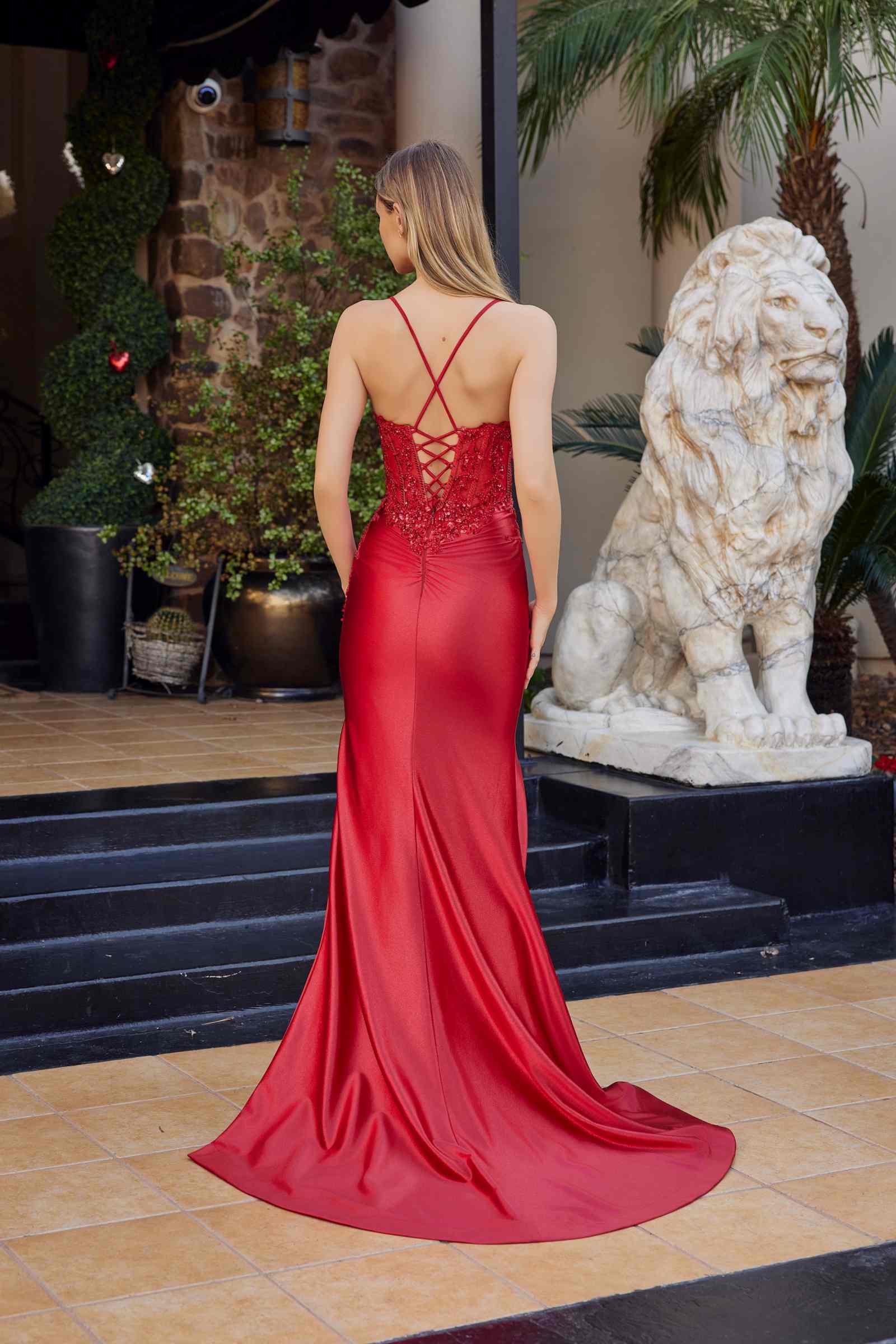 Red satin prom gown back view, crisscross strap detail, long skirt with flowing train