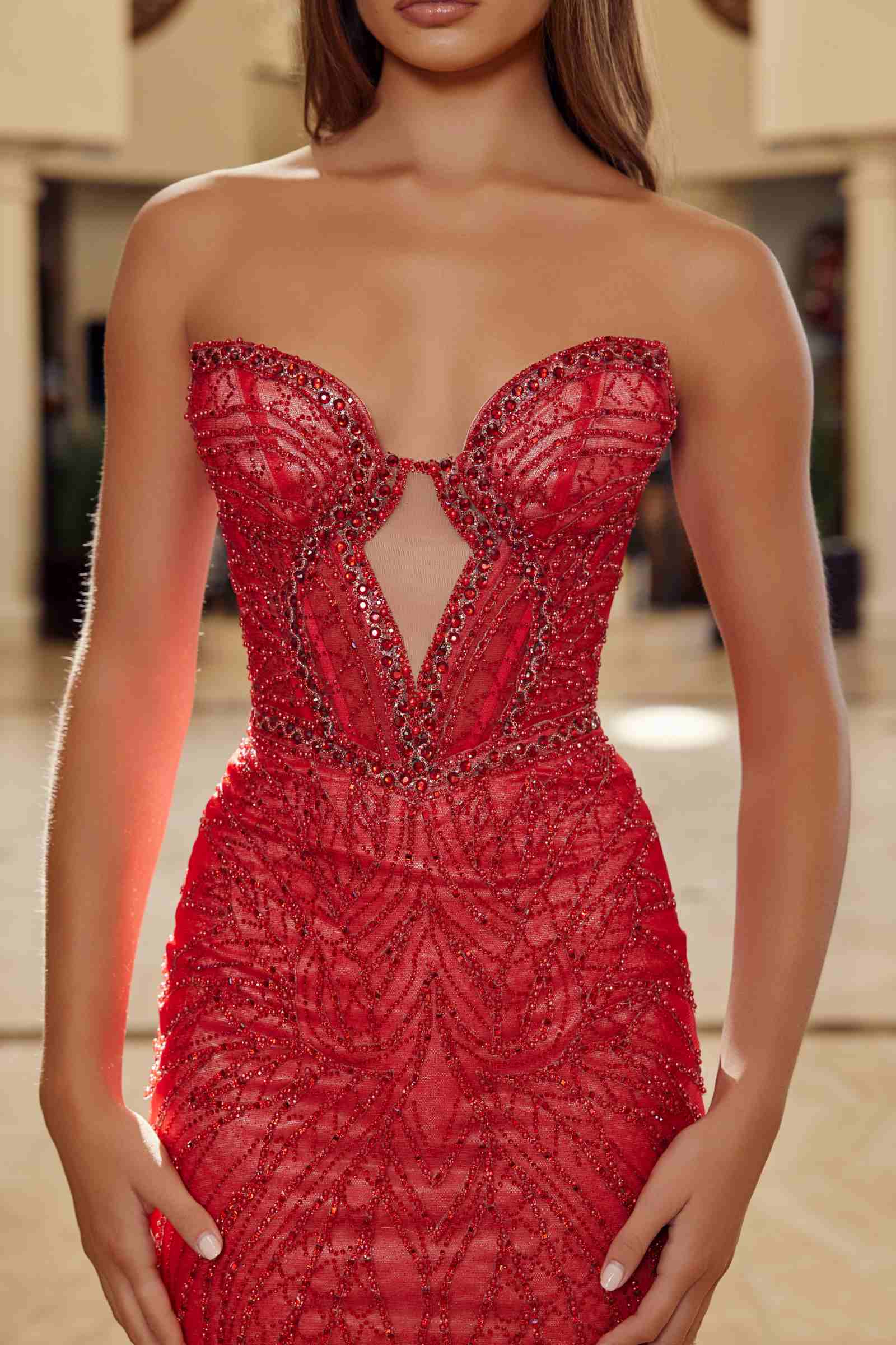 Red strapless keyhole bodice gown with ornate beadwork and sheer tulle coverage