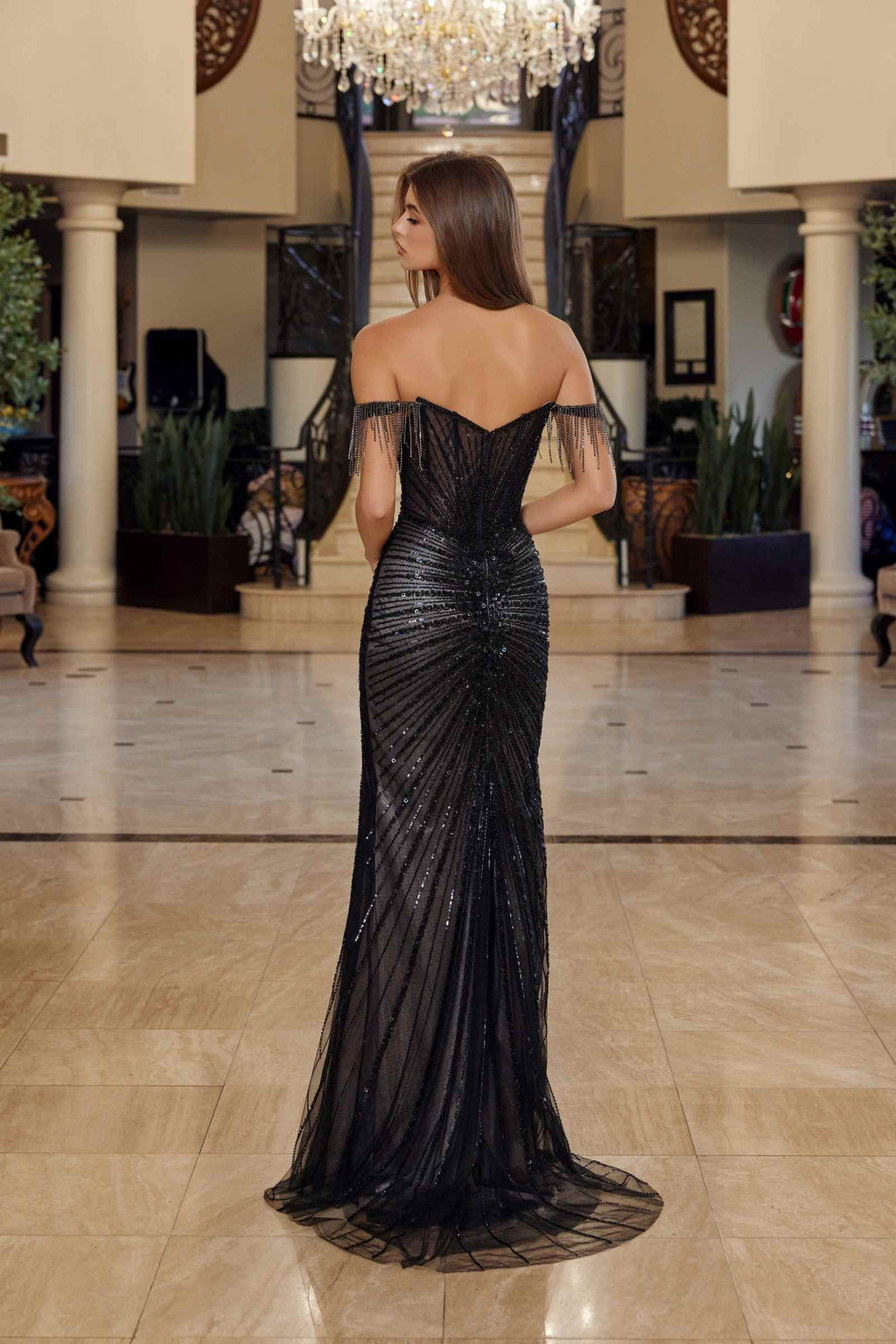 Back view of off-shoulder fitted beaded prom gown in dark black with long slit