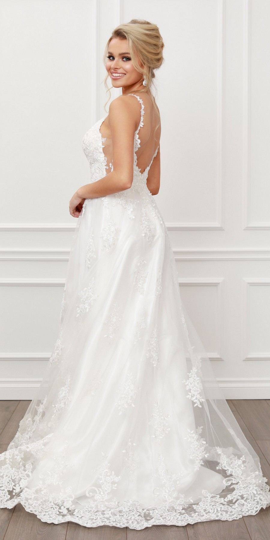 White lace A-line ball gown with open back, lace straps, and V-neck front.