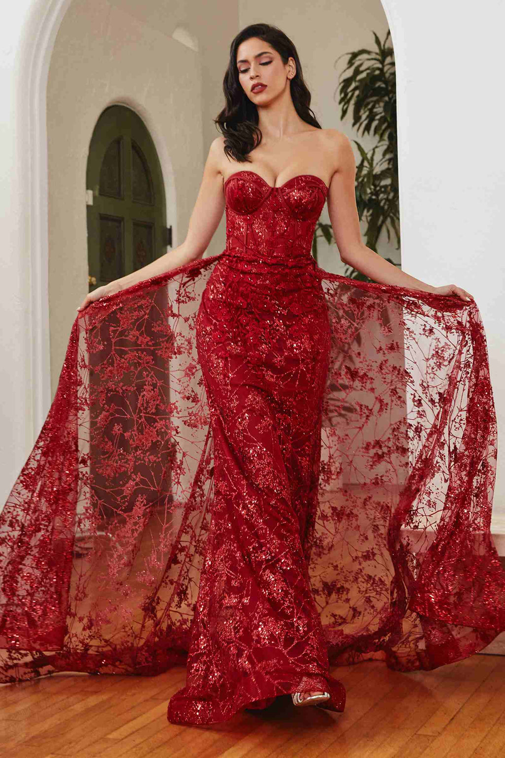 Deep red strapless fitted gown with glitter embroidery and flowing tulle overskirt panels