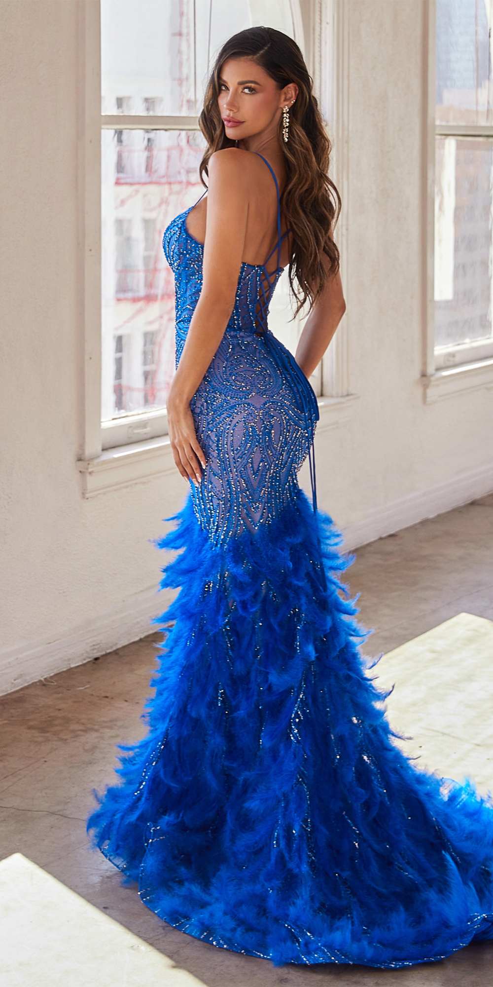 Blue embellished mermaid gown with feather fringe along the hem and spaghetti straps.