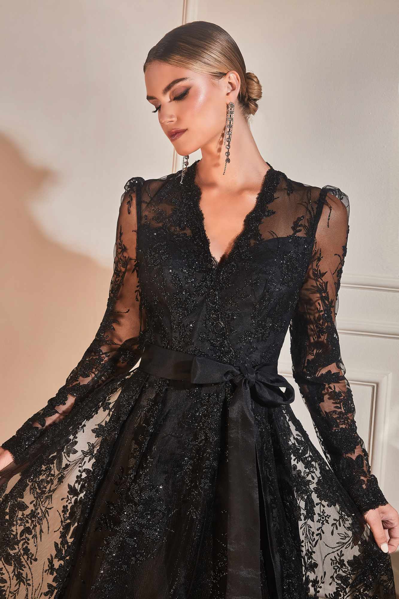 Black long-sleeve embellished ball gown with V-neck, sheer lace sleeves, and waist sash