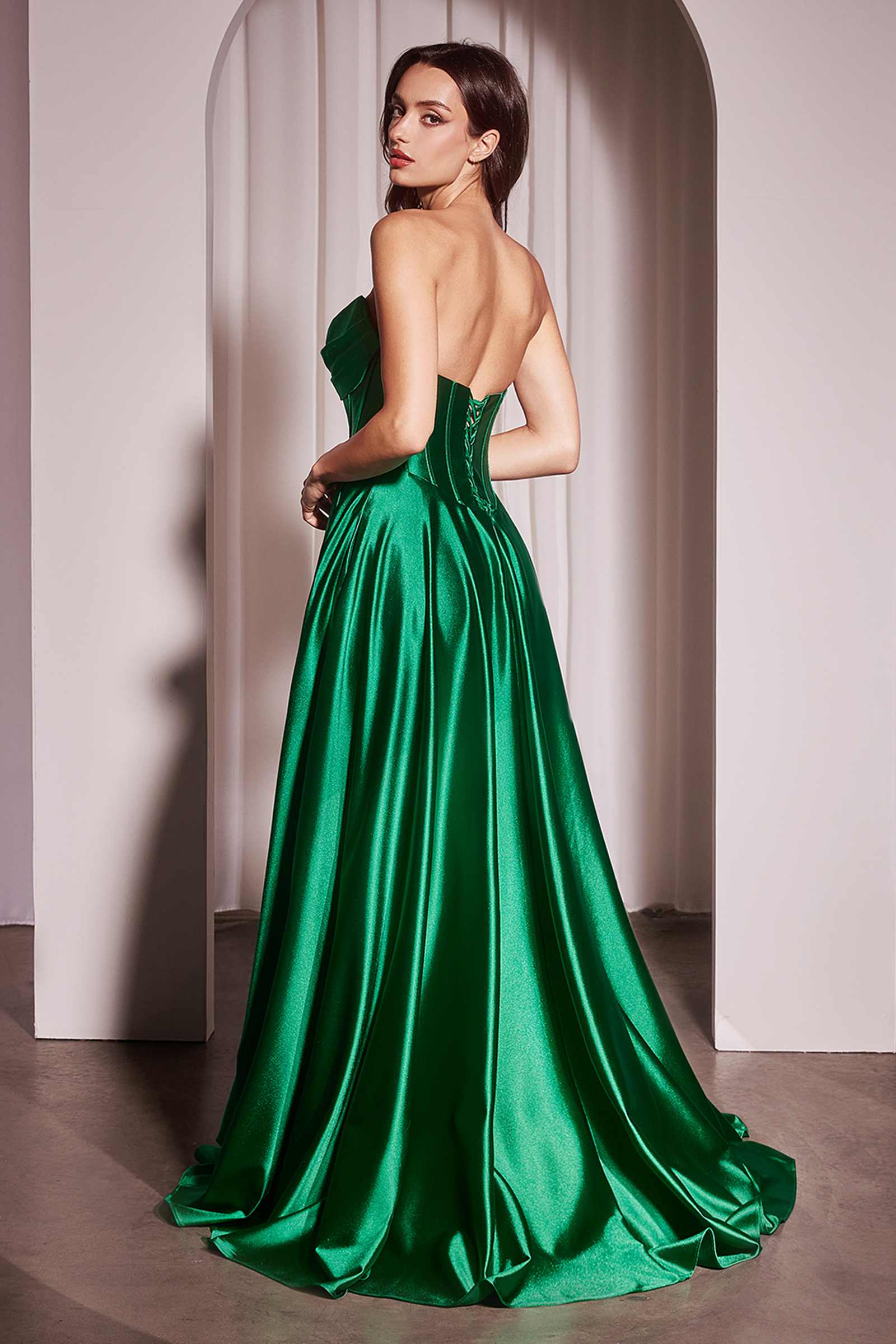 Back view of emerald green strapless satin A-line gown with corset-like shaping