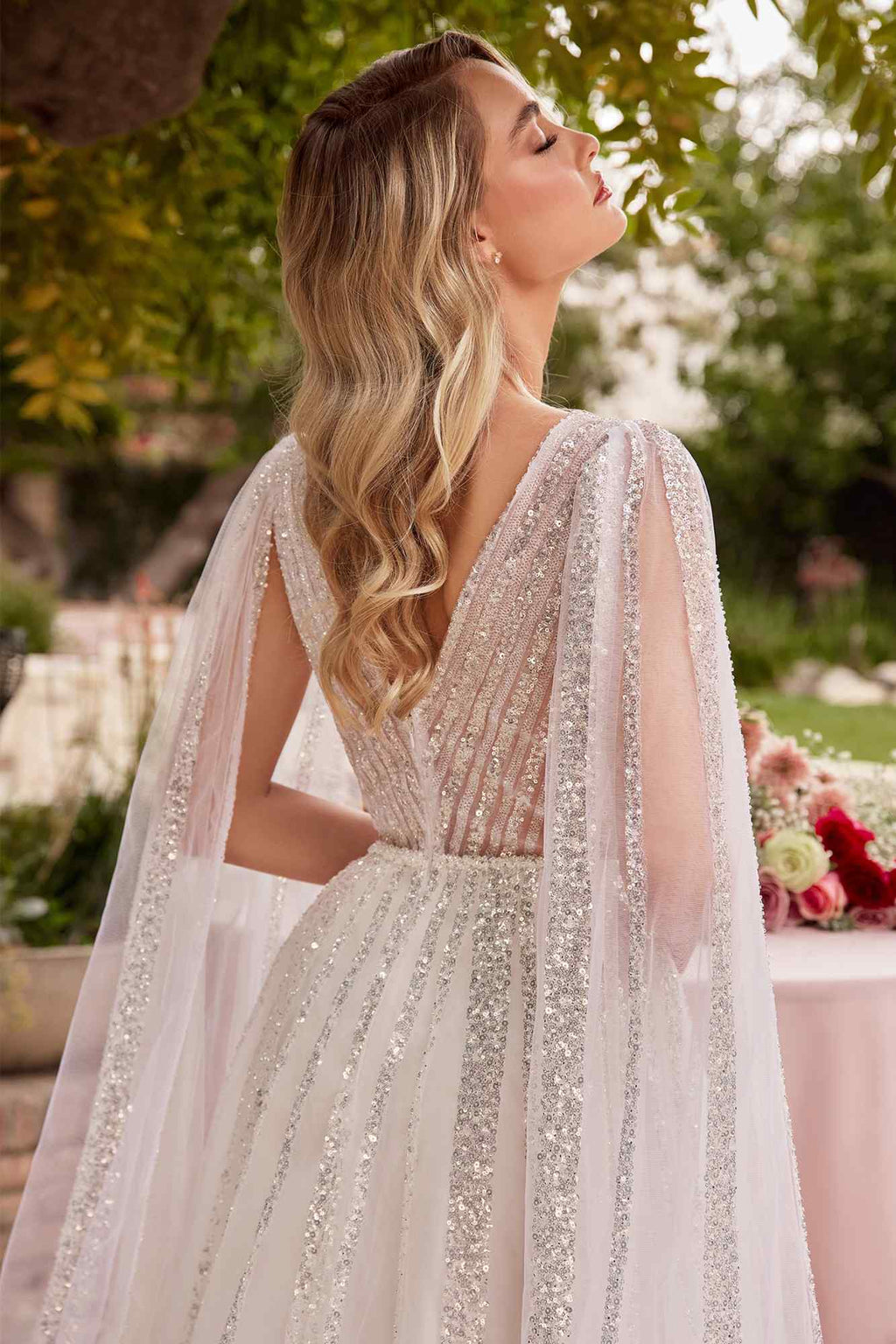 Off-white tulle wedding gown with V-neck bodice, shimmering texture, sheer cape sleeves