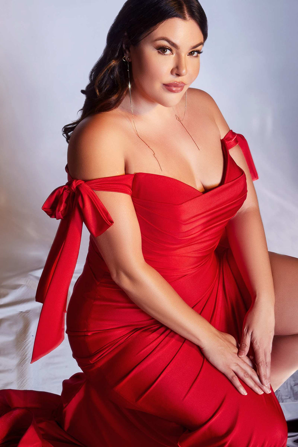 Off-shoulder fitted red jersey formal dress with bow shoulder ties and front slit.