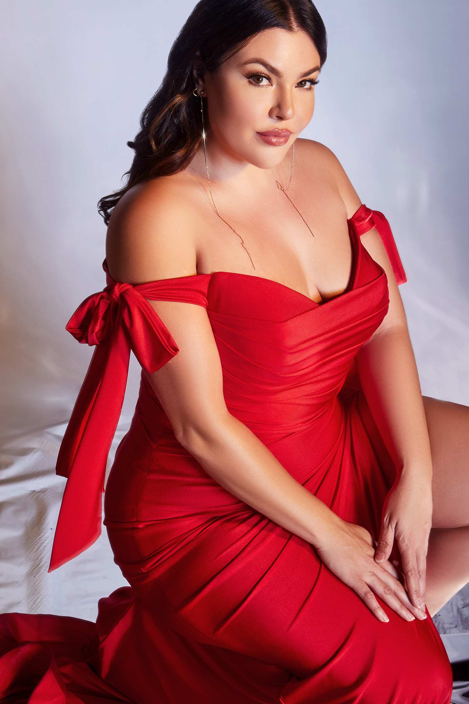 Off-shoulder fitted red jersey formal dress with bow shoulder ties and front slit.