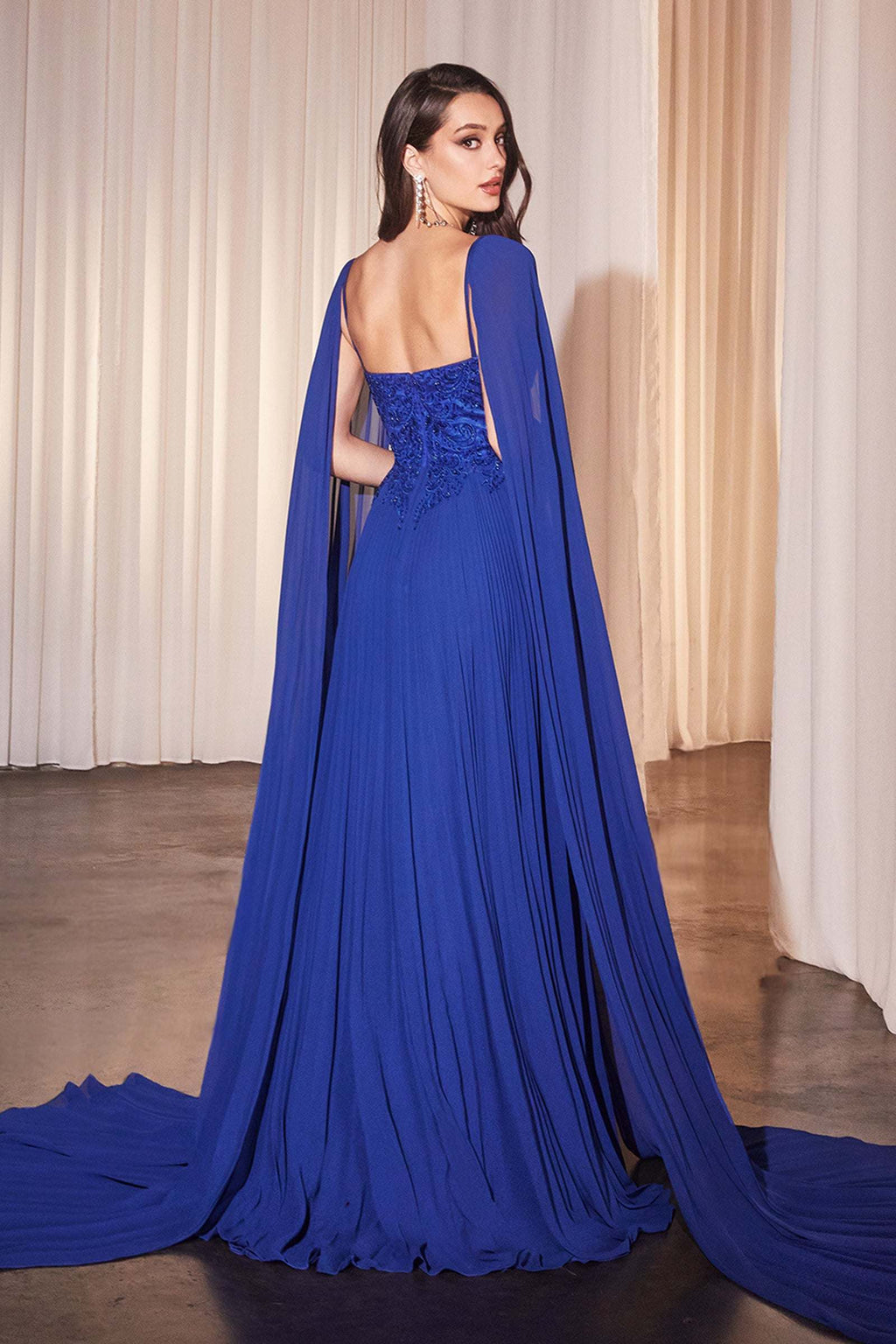 Royal blue pleated A-line gown with draped cape sleeves and embellished corset bodice