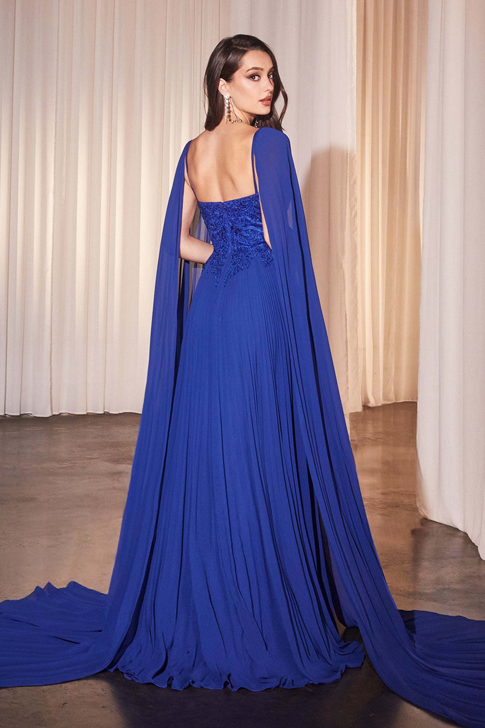 Royal blue pleated A-line gown with draped cape sleeves and embellished corset bodice