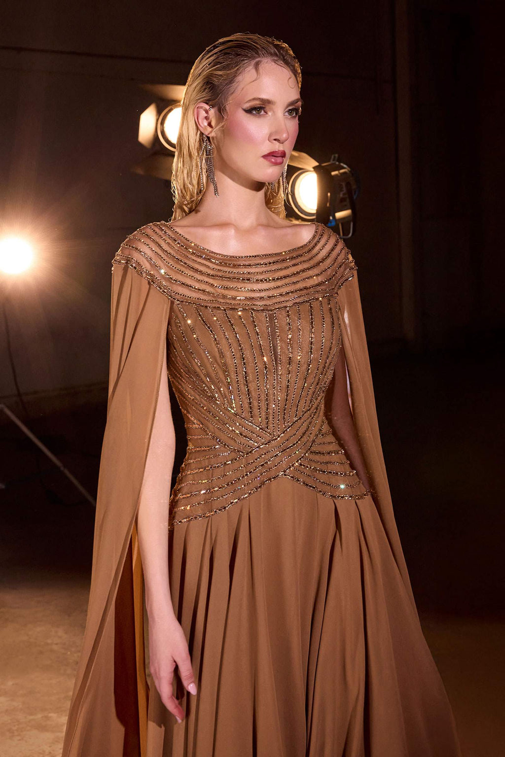Bronze A-line evening gown close-up: embellished off-shoulder bodice and cape