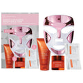Rose gold LED face mask set with orange serum bottles and white skincare packets