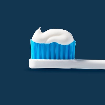 Electric toothbrush with white bristles and blue handle, resting on a blue base