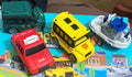 Toy vehicle set tray: red taxi, yellow bus, green van, white boat transport