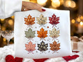 White graphic tee with colorful fall leaf pattern across the front