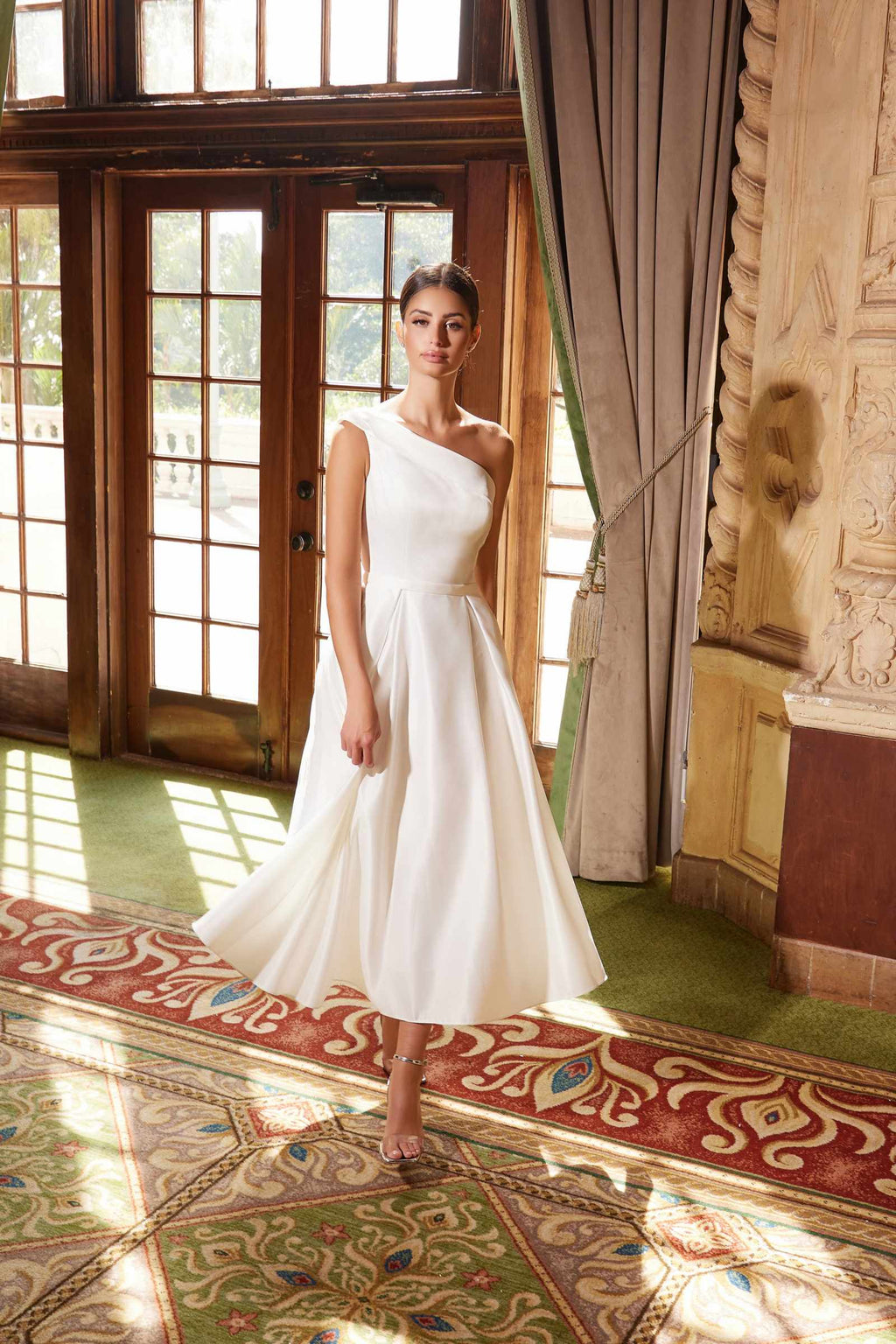 White one-shoulder satin tea-length gown with fitted bodice and full flared skirt