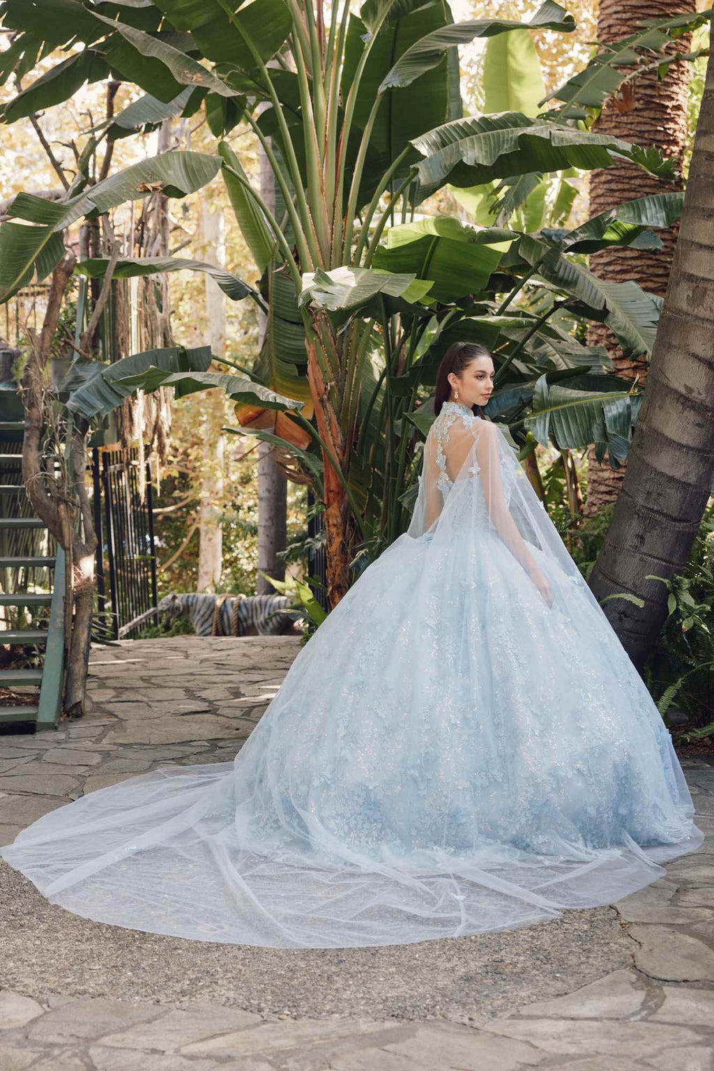 Light blue strapless sweetheart quinceanera gown with full skirt and sheer cape, back view