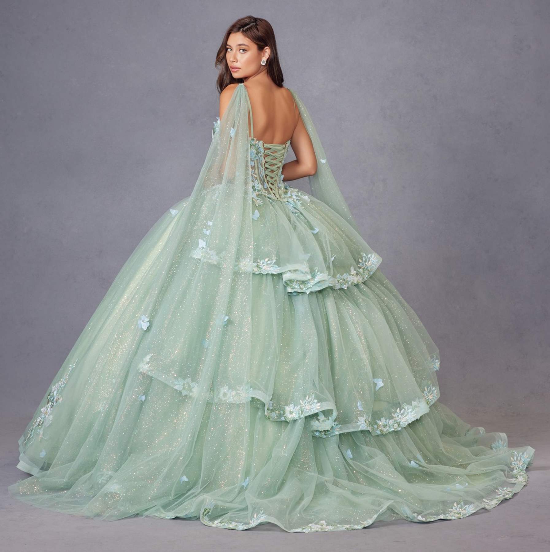 Sage green ballgown with tiered skirt, floral appliques, and sheer cape sleeves