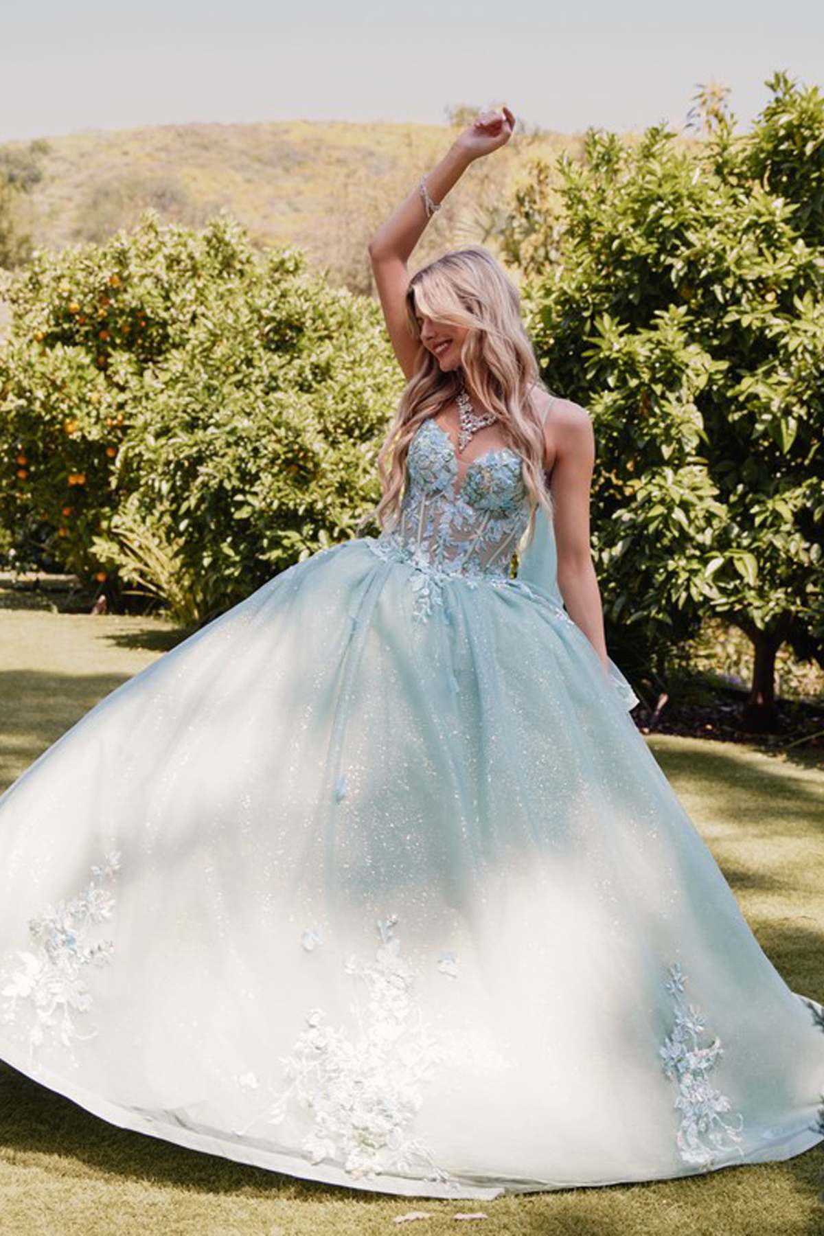 Sage green gown with floral appliques, sleeveless bodice, and flowing cape sleeve overlay