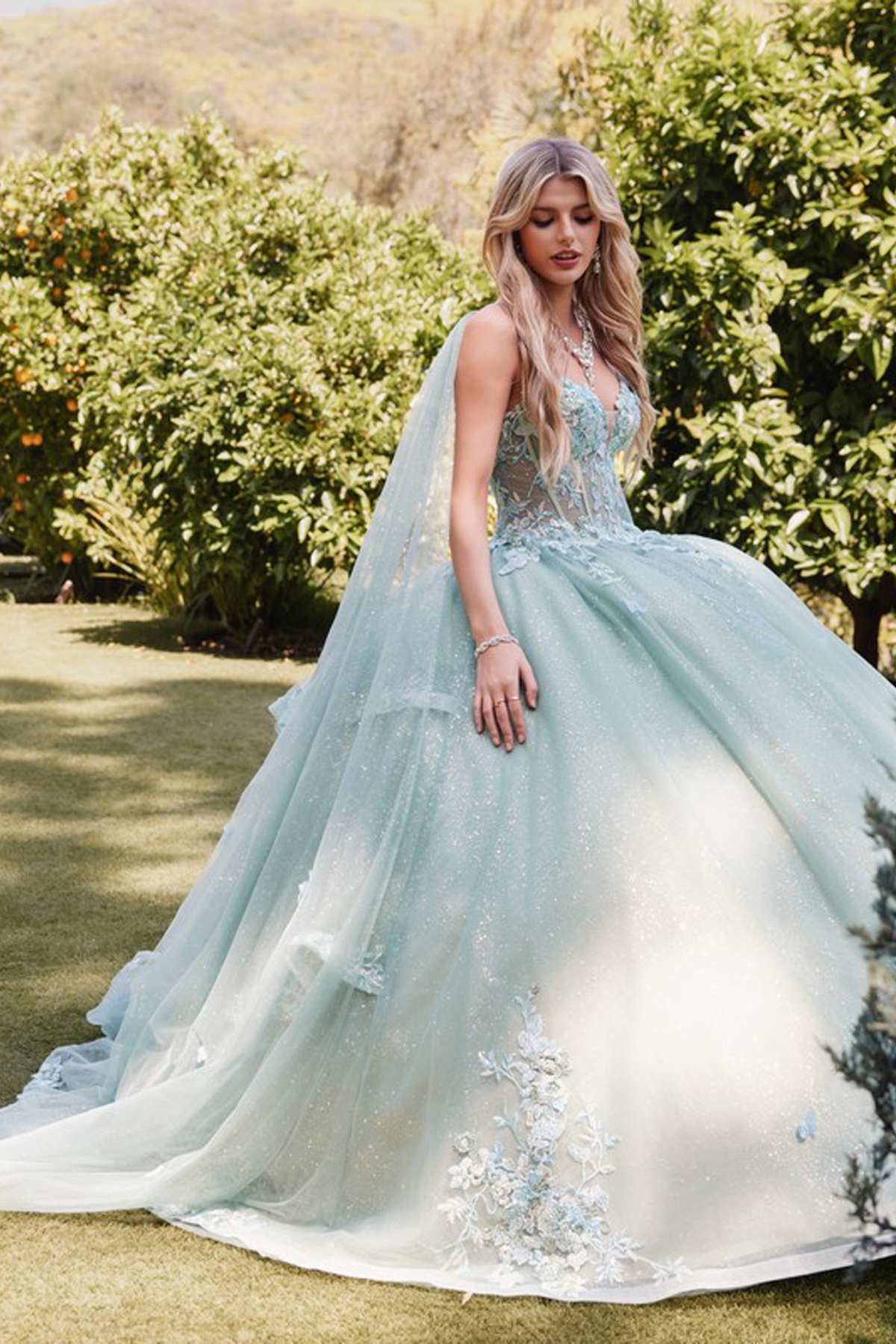 Sage green quinceanera gown with floral appliques and layered tulle skirt, side view