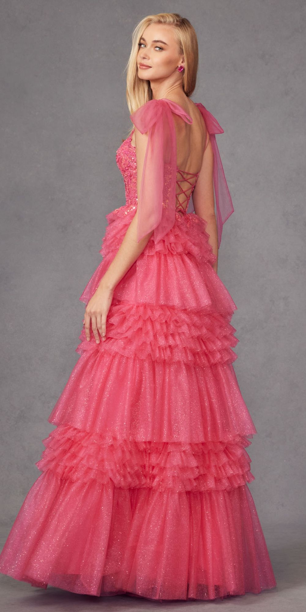 Fuchsia glitter tulle gown with sheer sleeves, open back, and tiered ruffle skirt