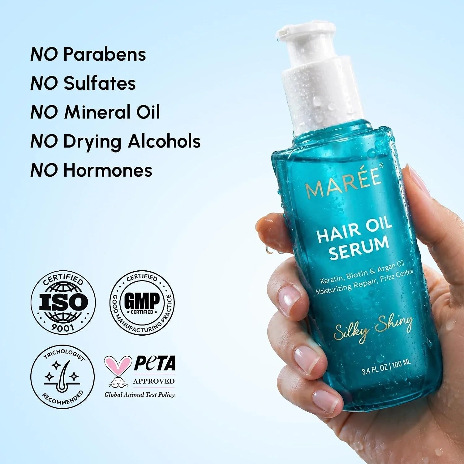 Hair oil serum bottle in teal held in hand with splash water droplets